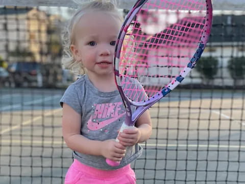 a little girl holding a tennis racket