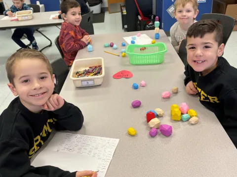 a group of children sitting at a table with toys