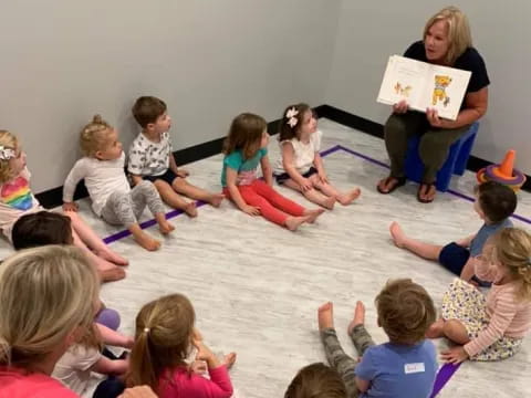 a person reading a book to a group of children