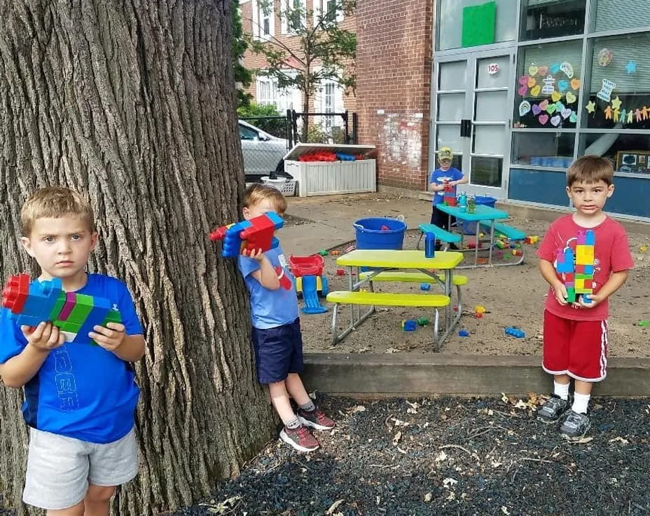 a group of boys standing next to a tree and a building