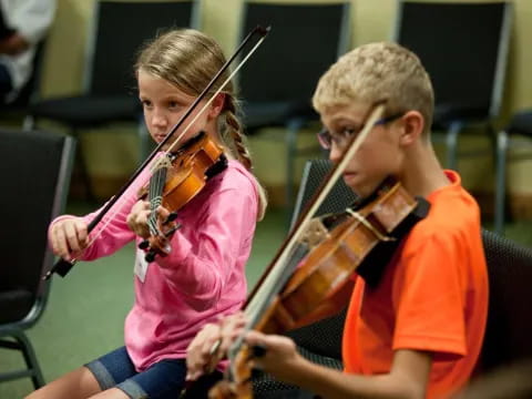 a boy and girl playing the violin