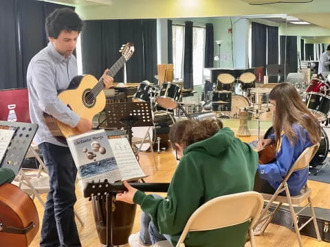a person playing a guitar in front of a group of people