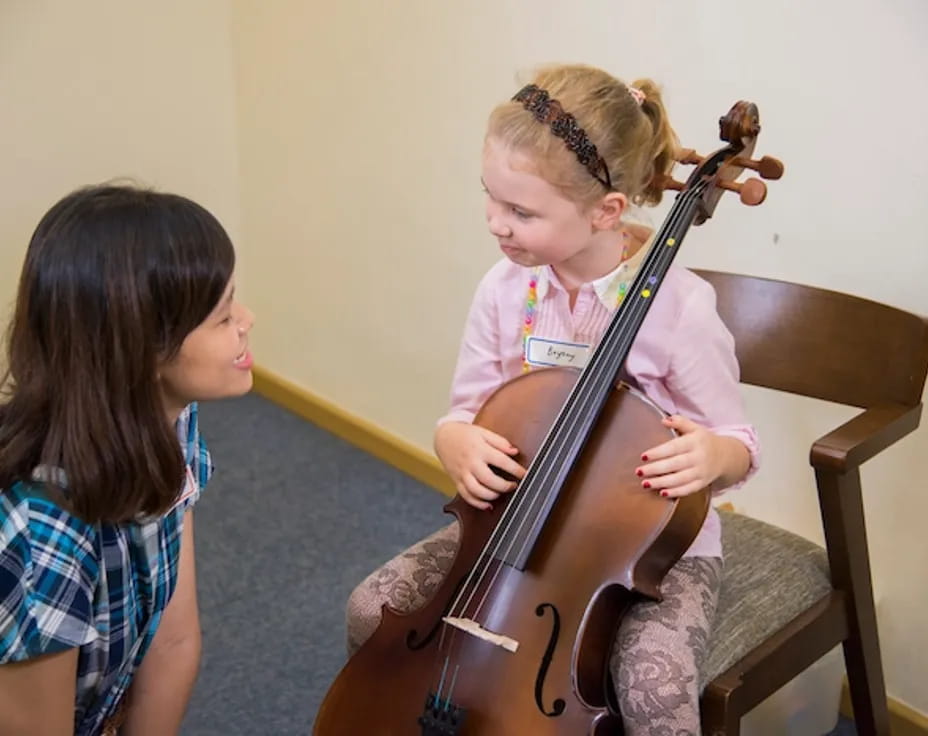 a girl playing a cello next to a girl