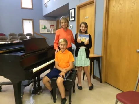 a group of people posing for a photo in front of a piano