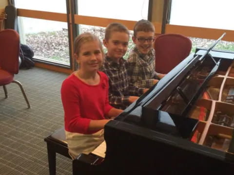 a group of people sitting at a piano