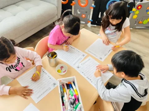 a group of children sitting at a table writing on paper