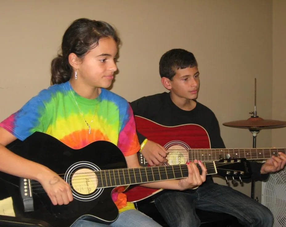 a man playing a guitar next to a boy