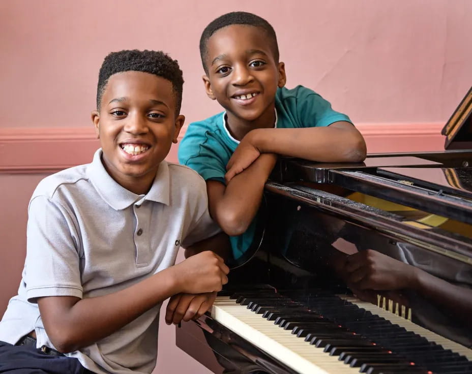 a couple of boys playing a piano