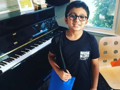 a boy standing next to a piano