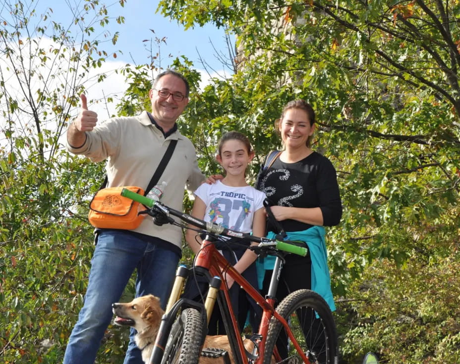 a man and a woman on a bicycle with a dog