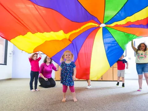 a group of people posing for a photo under a colorful umbrella