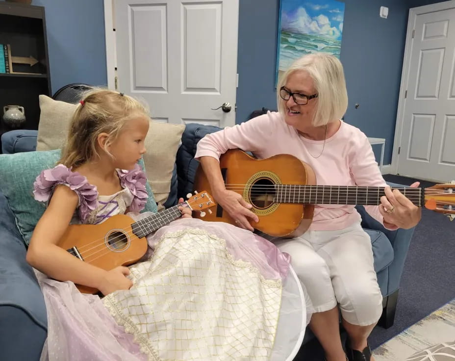 a person playing a guitar next to a girl sitting on a couch