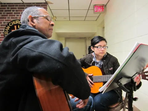 a man playing guitar next to a woman