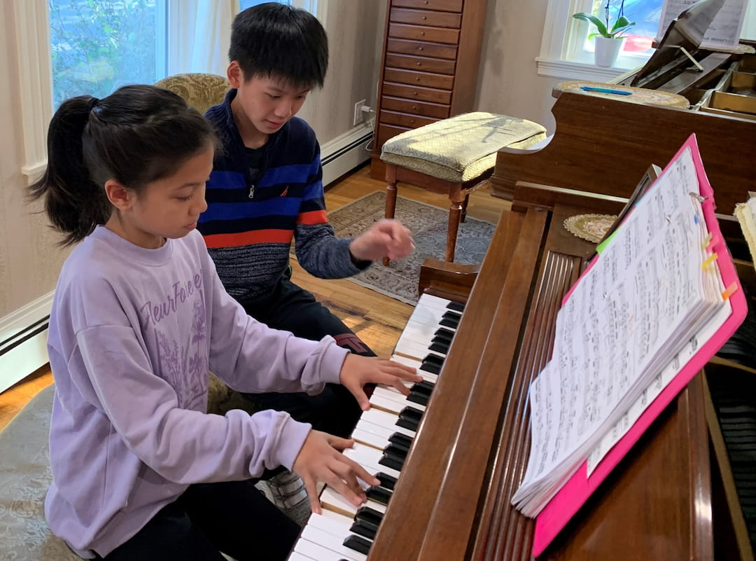 a boy and girl playing piano