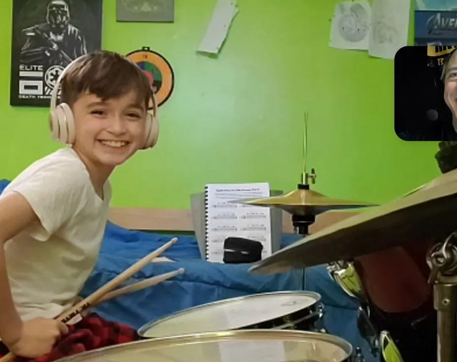 a boy wearing headphones and playing drums