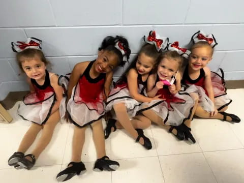 a group of girls wearing red and white dresses and sitting on the floor