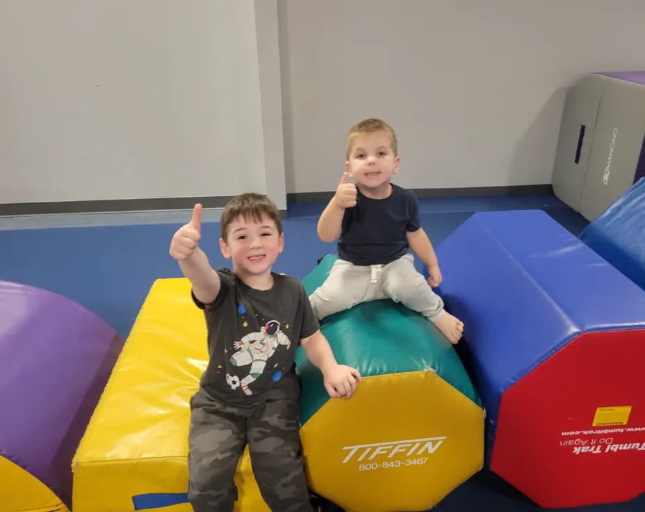 two boys sitting on a large yellow and blue toy