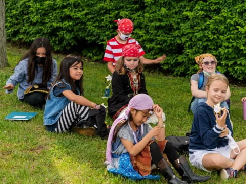 a group of people sitting on the grass with a person in a santa hat and a red and