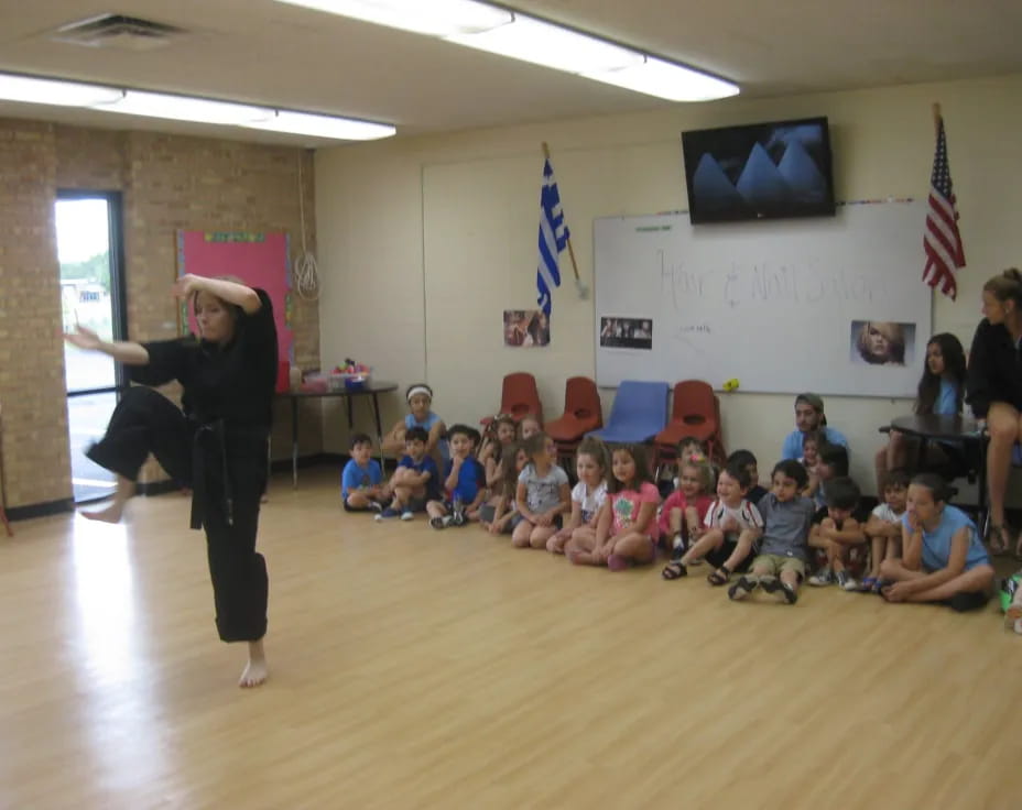 a person standing in front of a group of children sitting on the floor