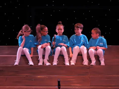 a group of children sitting on a stage