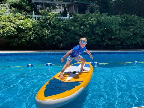 a boy on a surfboard in a pool