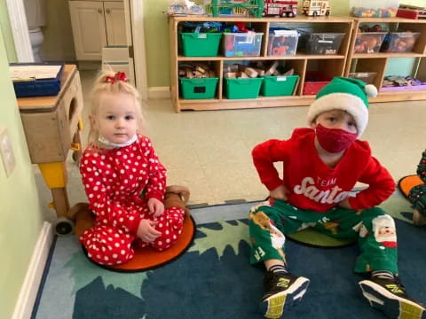 a girl and a boy sitting on a toy in a room with shelves