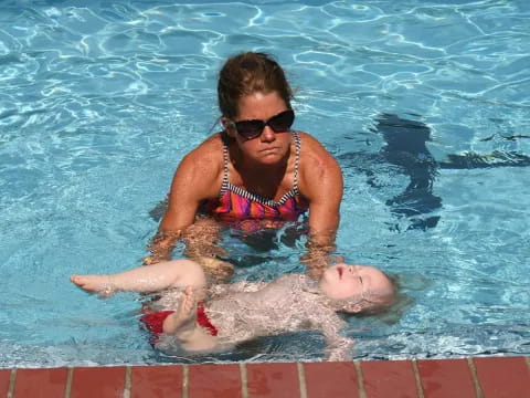 a man in a pool with a baby in his lap