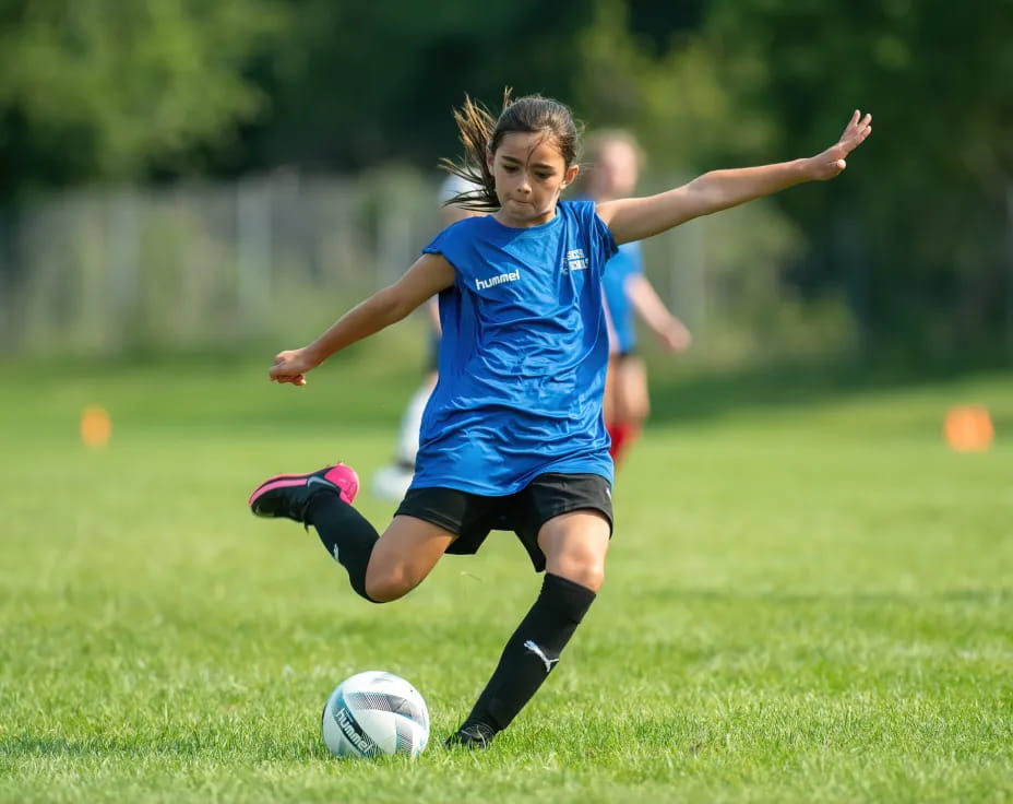 a girl kicking a football ball