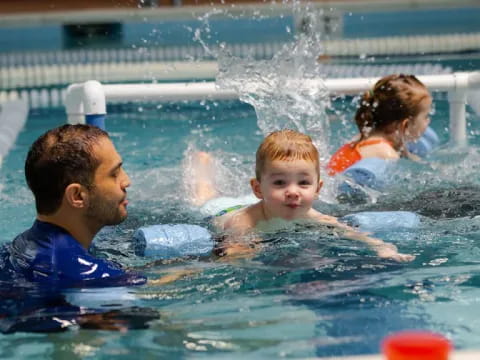 a man and a woman in a pool with a baby in it