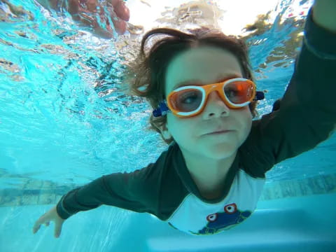 a woman wearing goggles and swimming underwater