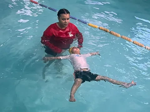 a person holding a baby in a pool