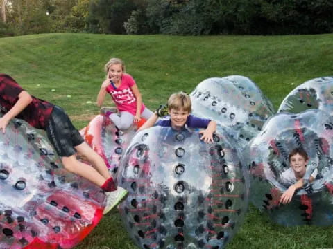a group of kids sitting on a large sculpture in a grassy area
