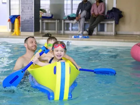 a person and a child in a pool with paddles and balls