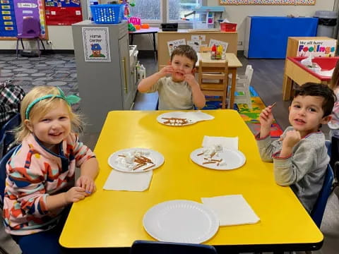 a group of children sitting at a table eating food