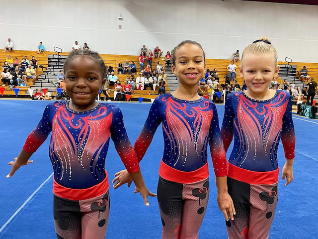 a group of girls in leotards posing for a photo