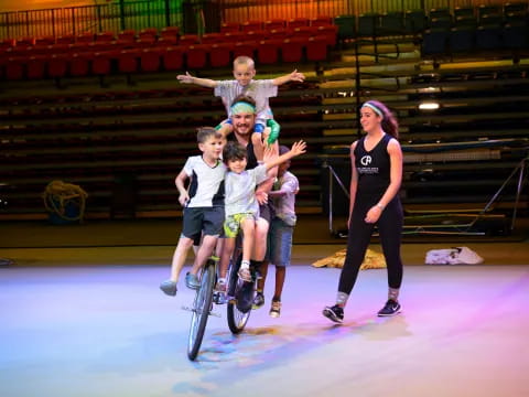 a man and a group of kids on a bike in a gym