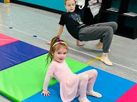 a girl and a boy on a mat in a gym