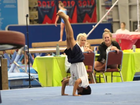 a person doing a handstand on a mat in a gym