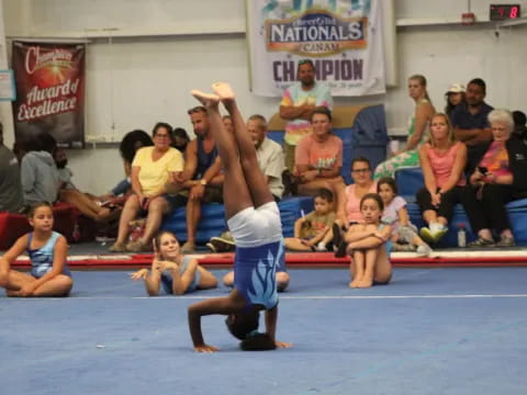 a person in a blue uniform doing a handstand in front of a crowd of people