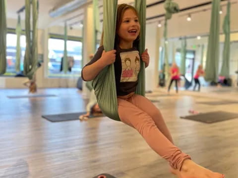 a girl sitting on a green pole