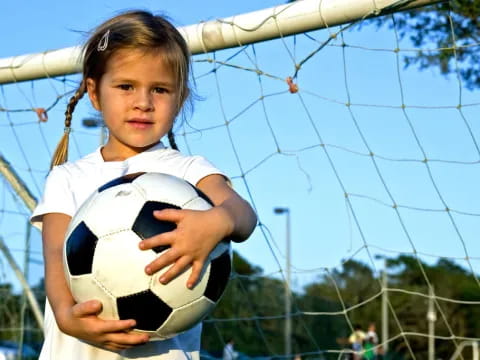 a girl holding a football ball
