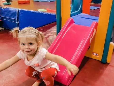 a girl sitting on a pink toy