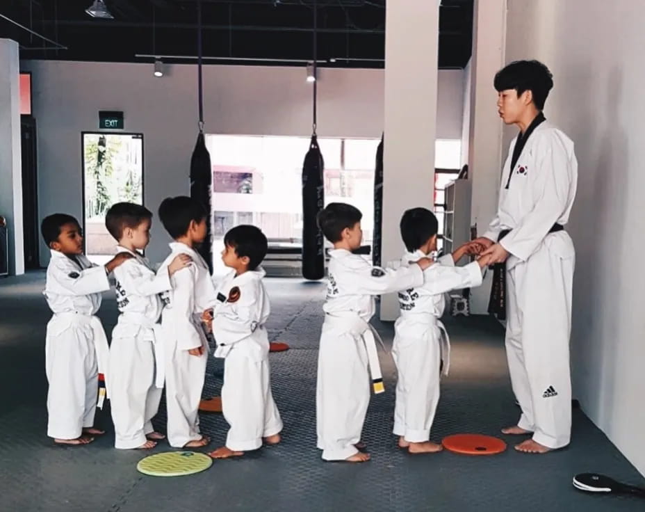 a man standing in front of a group of kids in karate uniforms