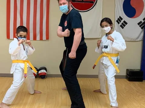 a person standing in front of a group of kids in karate uniforms