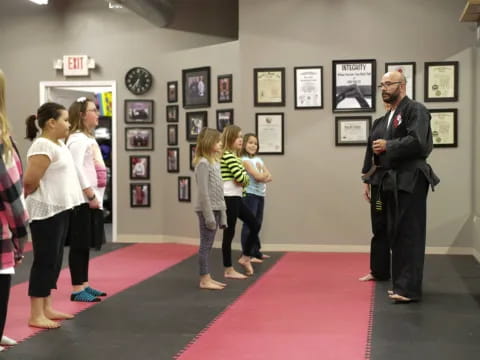 a person standing in front of a group of people in a room with pictures on the wall