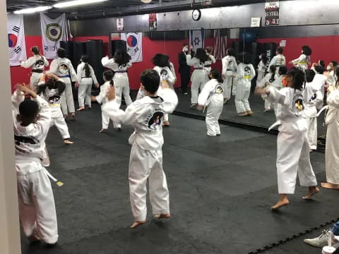 a group of people in white karate uniforms in a room with a red wall and a flag