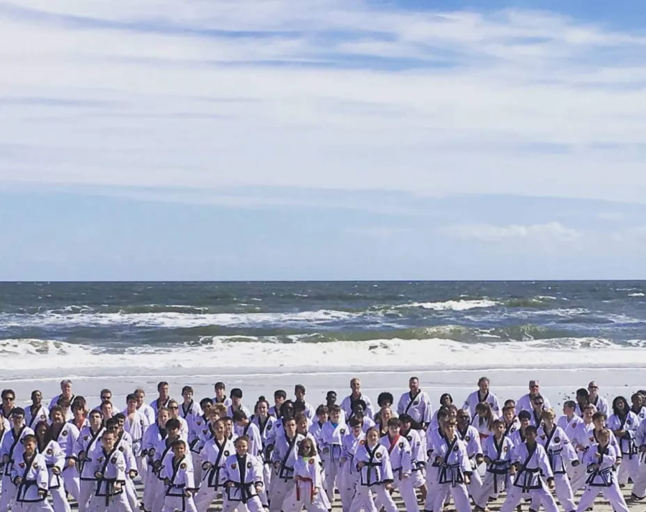 a large group of people in white and black robes on a beach