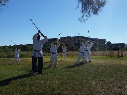 a group of people in white uniforms holding swords in a field
