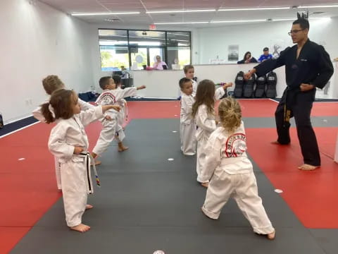 a person standing in front of a group of children in karate uniforms