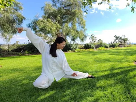 a man in a white dress stretching his arms out in a grassy field